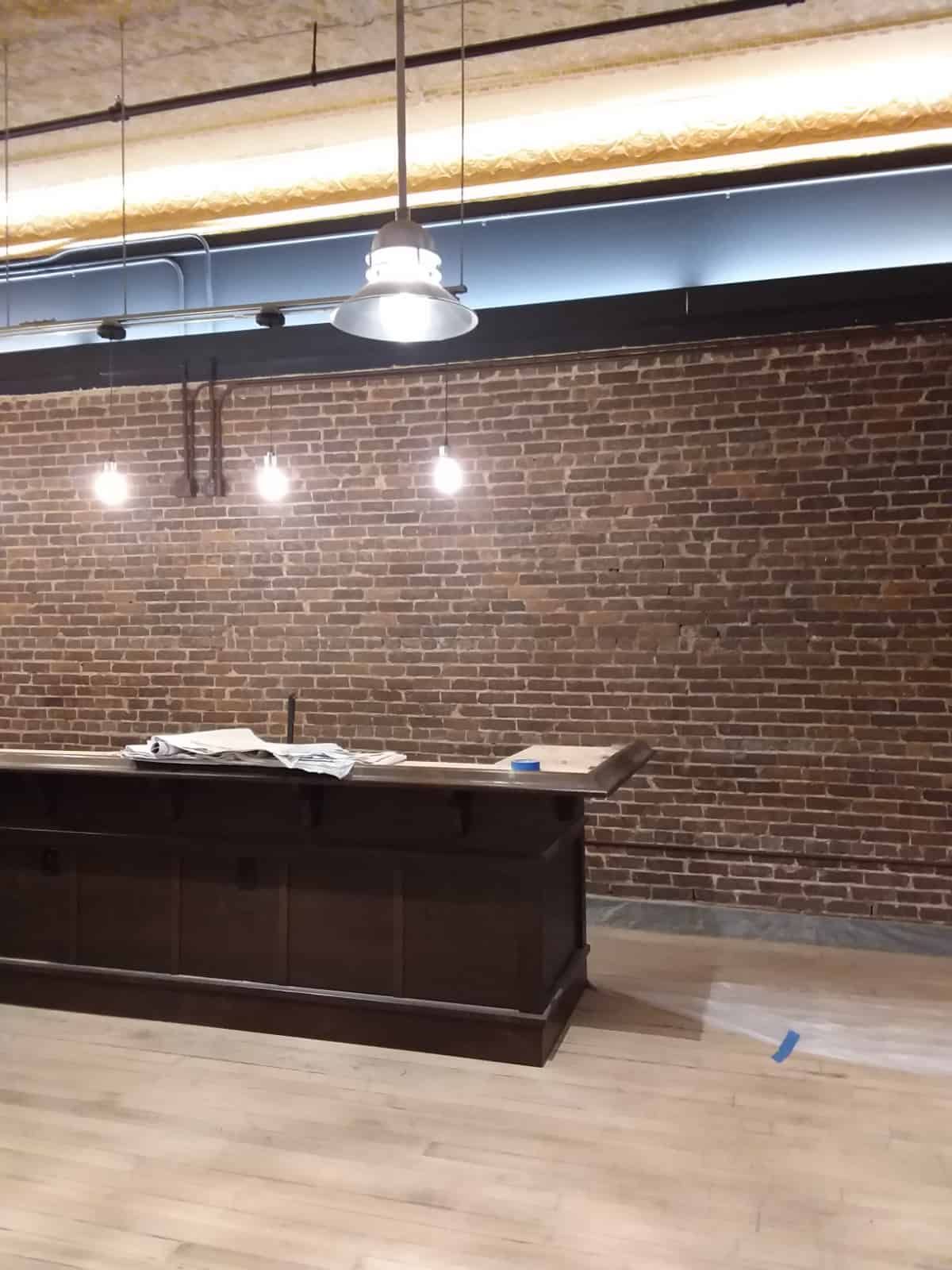 desk on wood floor with hanging lights in front of a brick wall