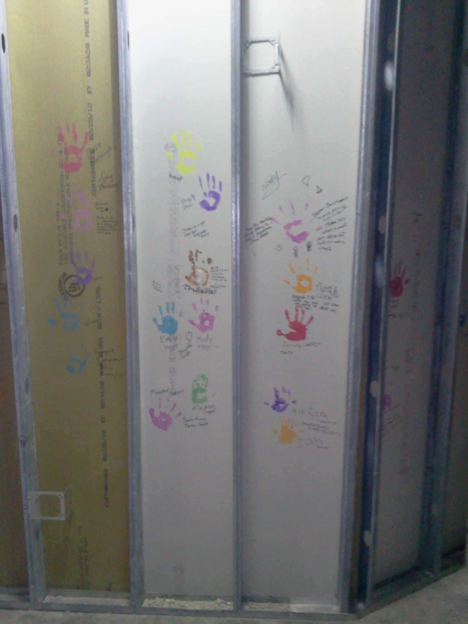 children's hand prints and signatures on under construction inner wall