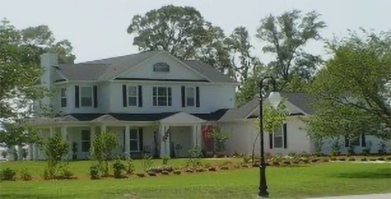 two-story white house with gray roof and green landscaping