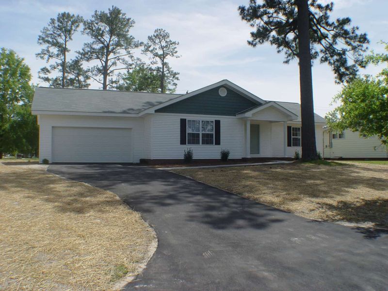 house with white siding, driveway, and tree
