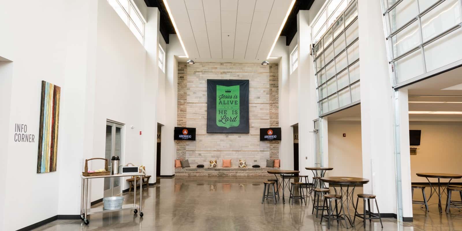 high ceiling room with tables, stools, and wood floor