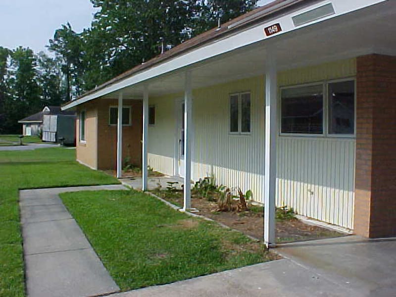 sidewalk leading to red brick house with white siding